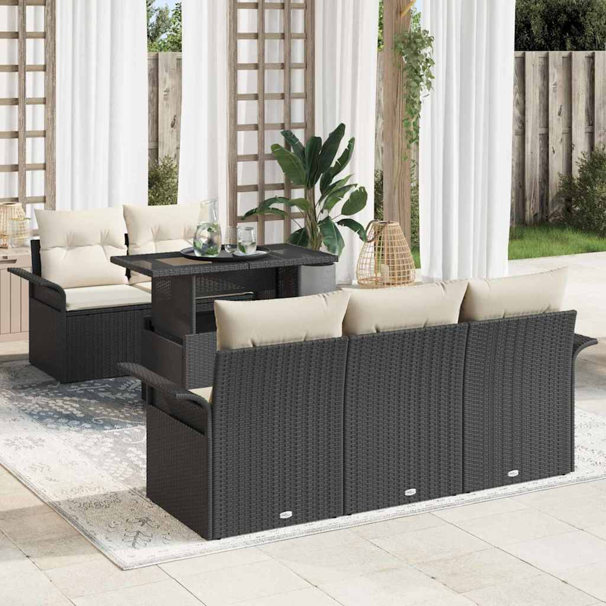 Juego de patio al aire libre con sofá y sillón de mimbre gris oscuro con cojines beige. Una mesa y una alfombra completan la escena, con cortinas blancas.