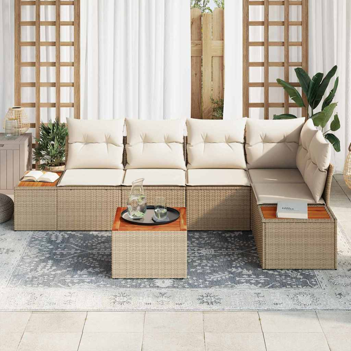 Zona de estar al aire libre con cojines beige y muebles de ratán. Una mesa con bandeja y una alfombra en primer plano.