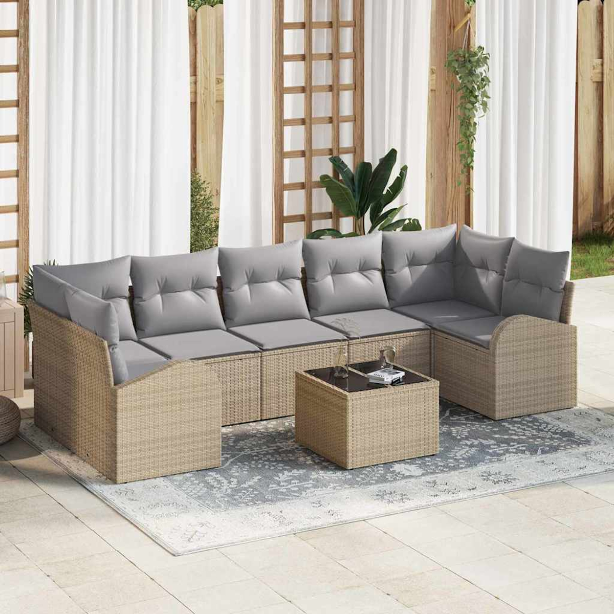 Outdoor-Wicker-Ecksofa mit grauen Kissen und einem passenden Couchtisch auf einem gemusterten Teppich. Weiße Vorhänge im Hintergrund.