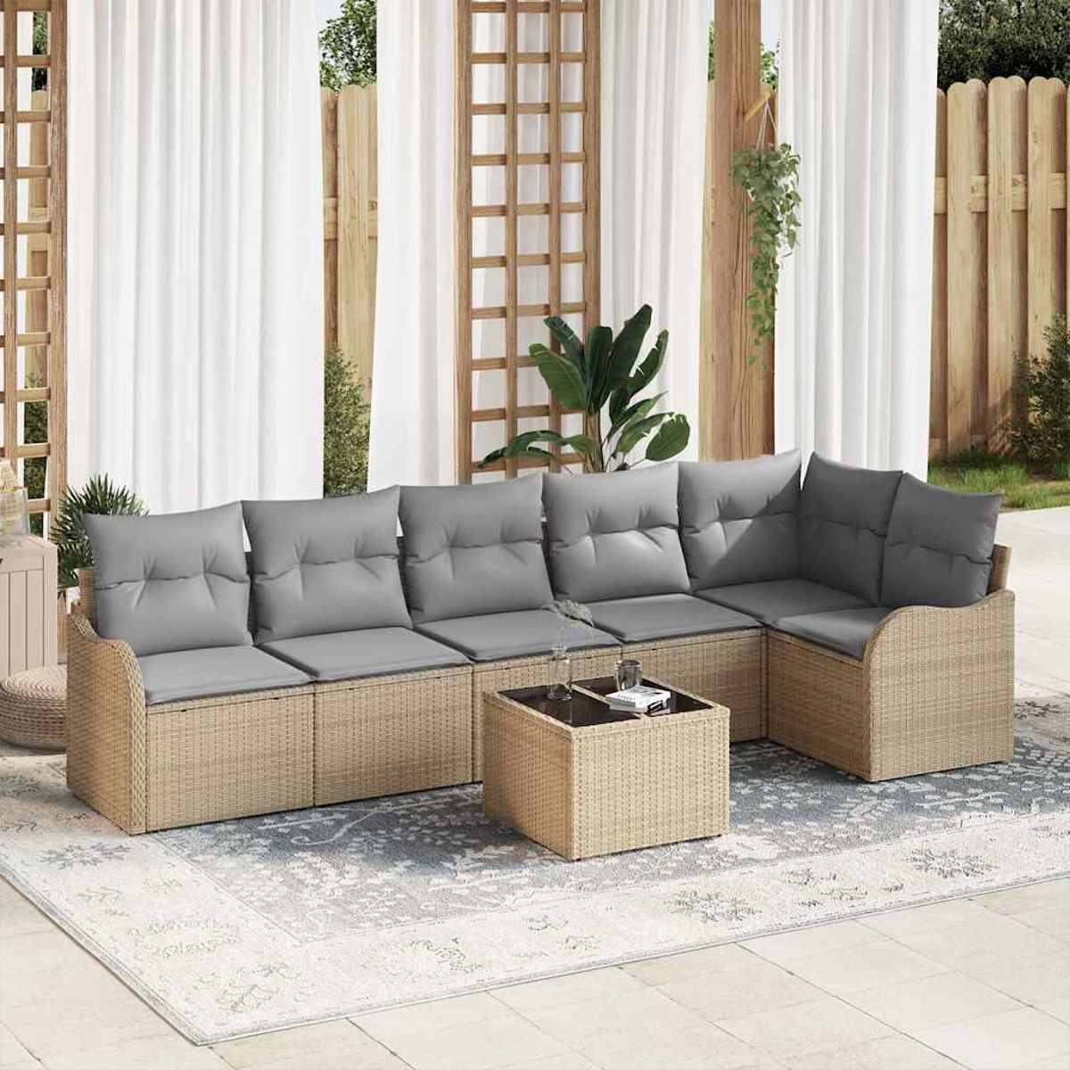 Outdoor-Ecksofa mit grauen Kissen, einem Korbgeweberahmen und einem quadratischen Couchtisch. Weiße Vorhänge und Holzgitter im Hintergrund.
