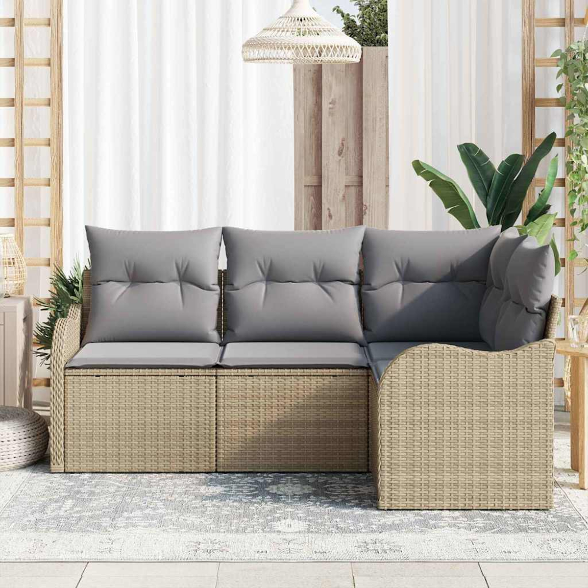 Geflochtenes Ecksofa mit grauen Kissen auf einer Terrasse. Weiße Vorhänge, Pflanzen und eine gewebte Leuchte sind im Hintergrund.