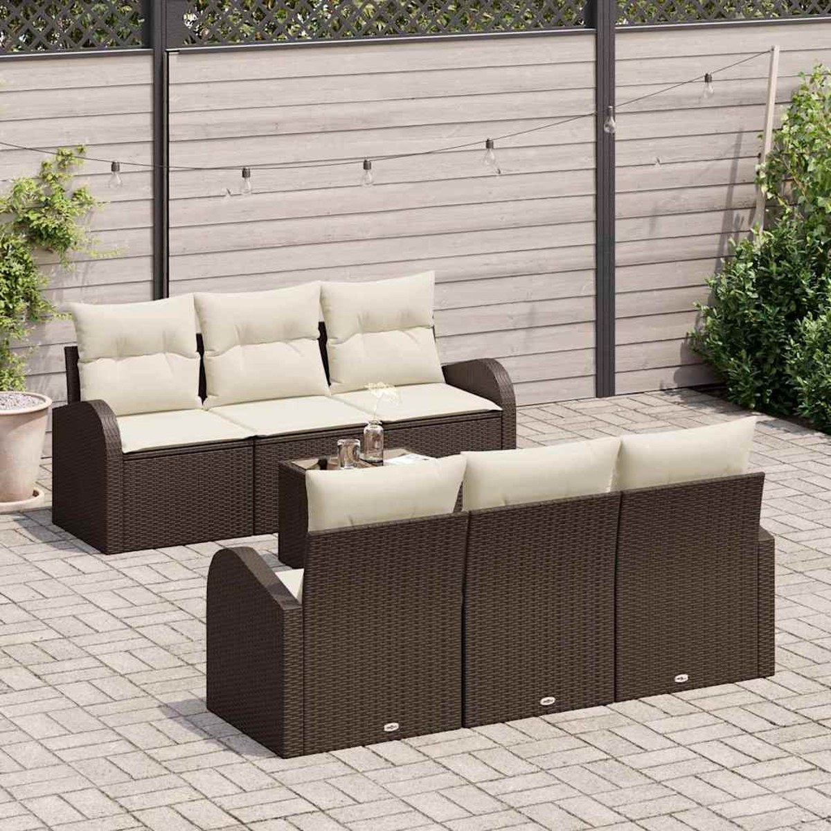 Terrassenset im Freien. Braune Korbsessel mit cremefarbenen Kissen. Kleiner Tisch mit Gläsern. Holzzaun im Hintergrund.