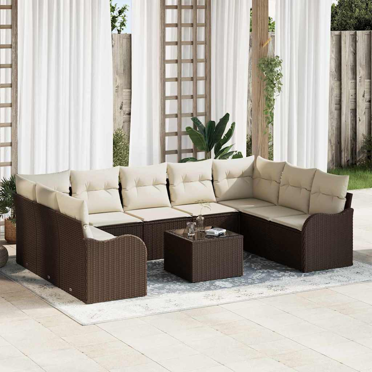 Outdoor-Ecksofa mit beigen Kissen und einem passenden Couchtisch auf einem Teppich. Weiße Vorhänge und Holzzaun sind im Hintergrund.