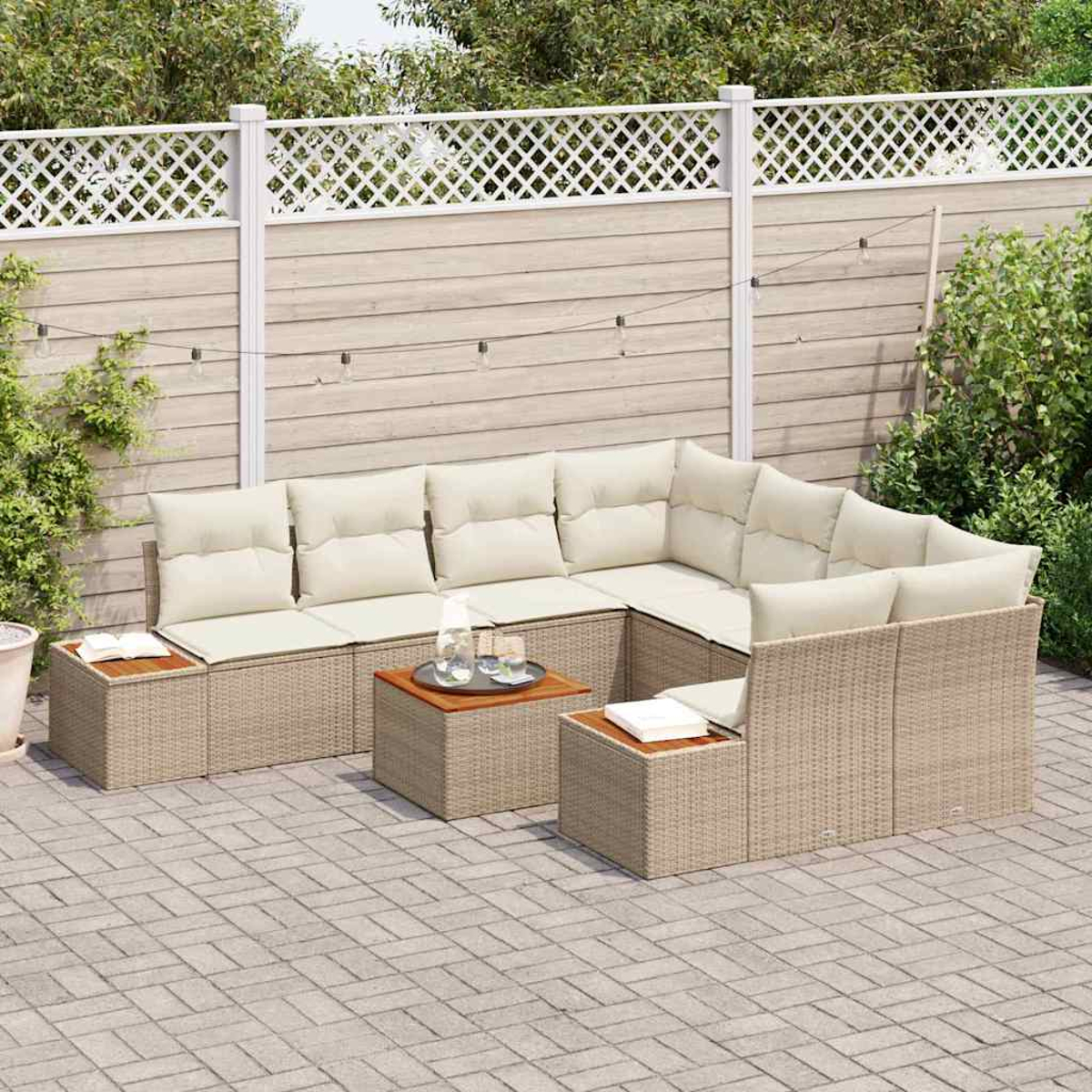 Ein Ecksofa im Freien mit beigefarbenen Kissen und gewebtem Korbgeflecht. Inklusive zweier kleiner Tische und einem weißen Zaun im Hintergrund.