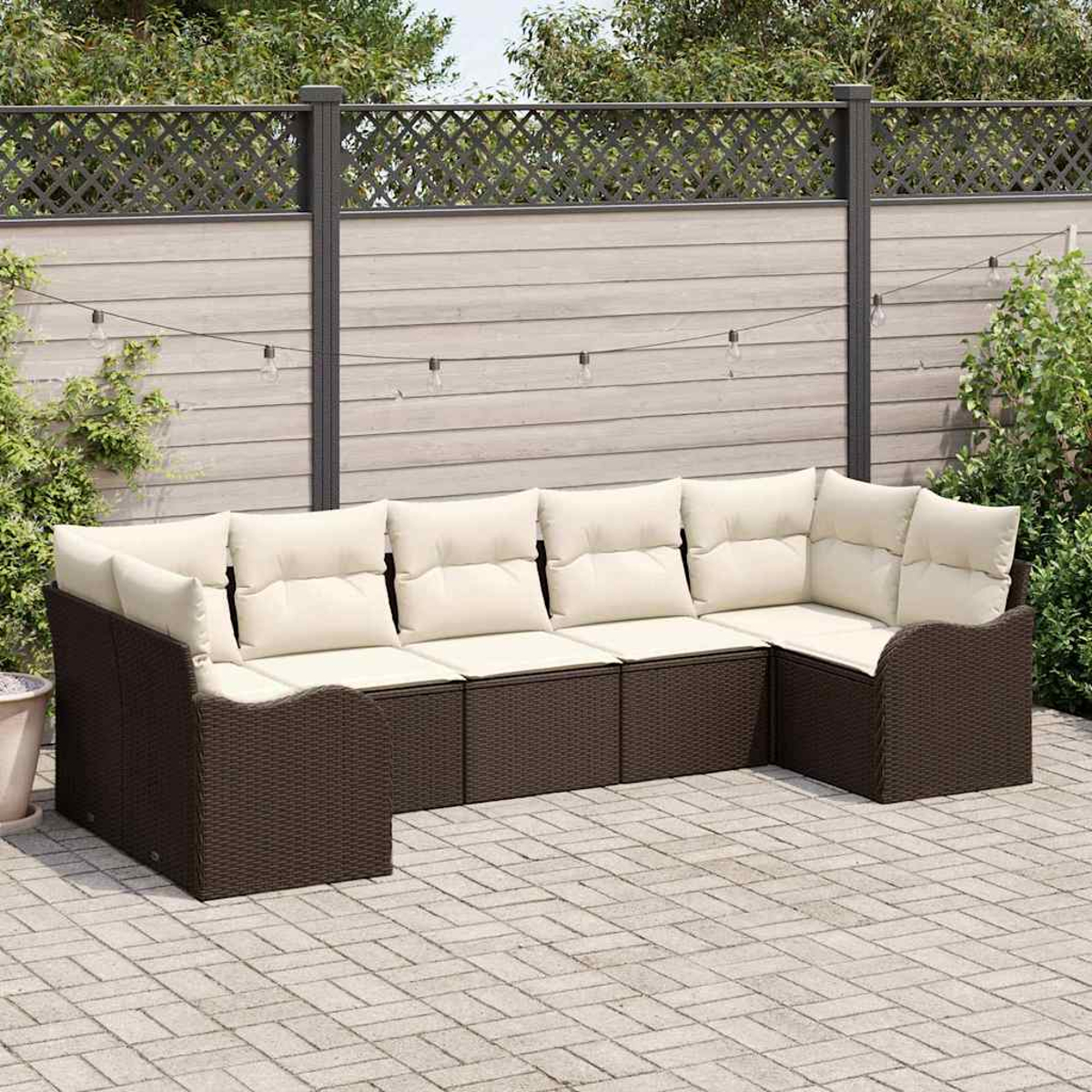 Ein braunes Korbsessel-Ecksofa mit cremefarbenen Kissen steht auf einer Ziegelterrasse. Ein Holzzaun und Lichterketten sind im Hintergrund.