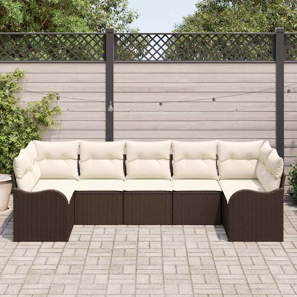 Ein Ecksofa im Freien mit cremefarbenen Kissen und braunem Korbbasiss steht auf einer Steinterrasse. Ein Zaun und Laub sind im Hintergrund.