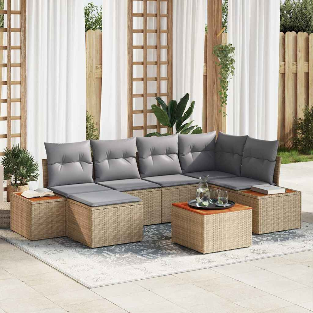 Outdoor-Sitzgruppe mit grauen Kissen auf gewebter Basis, Couchtisch mit Tablett und weiße Vorhänge im Hintergrund.