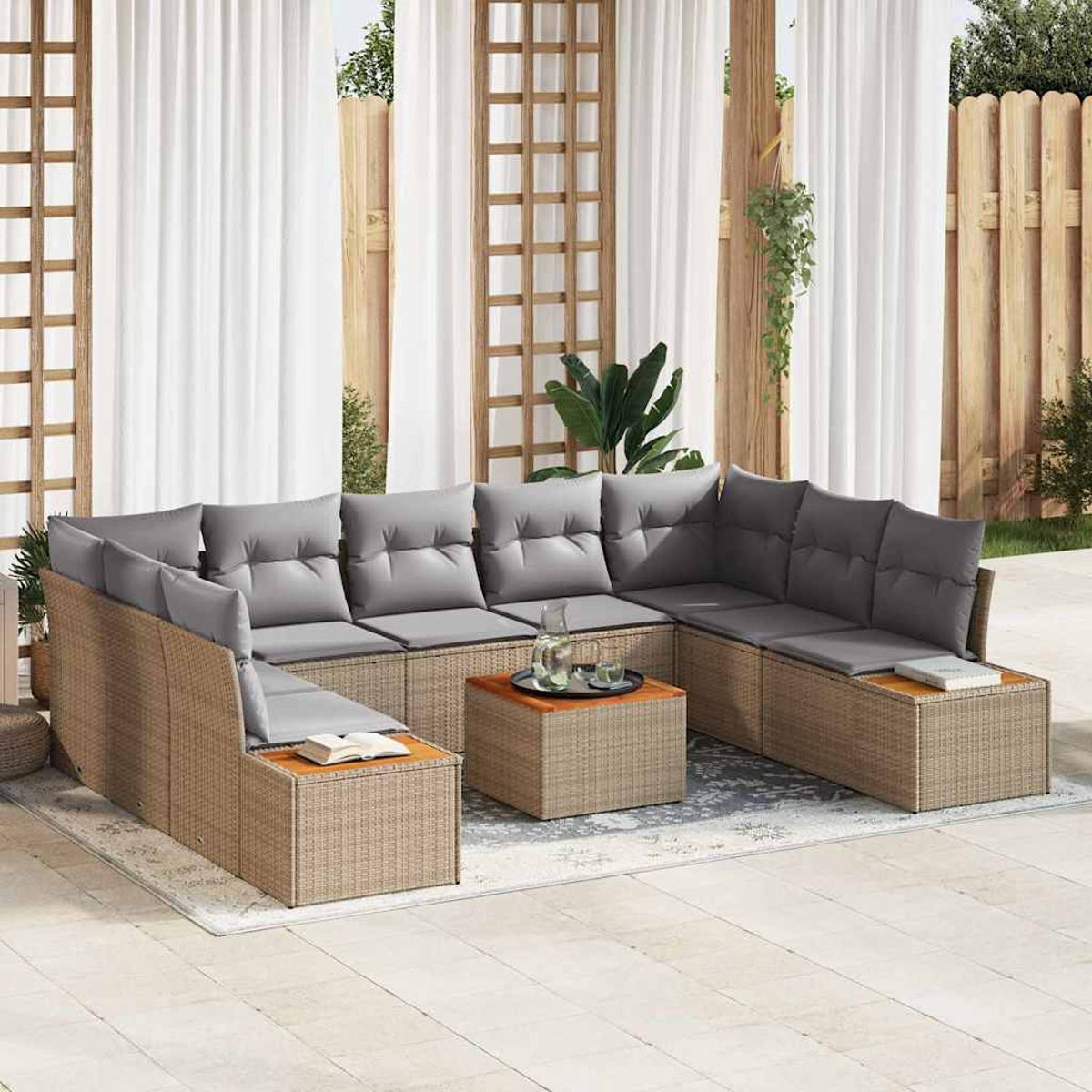 Outdoor-Korbsessel mit grauen Kissen. Ein Couchtisch mit Gläsern steht in der Mitte. Weiße Vorhänge und ein Holzzaun im Hintergrund.