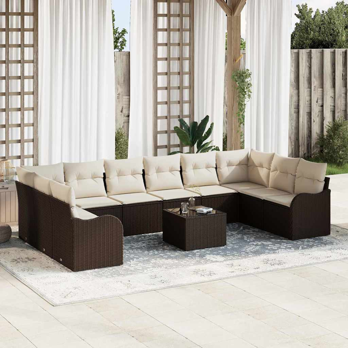 Outdoor-Sitzbereich mit braunem Korbmöbel-Sofa und beigefarbenen Kissen, kleinem Tisch und weißen Vorhängen. Die Szene ist hell und einladend.