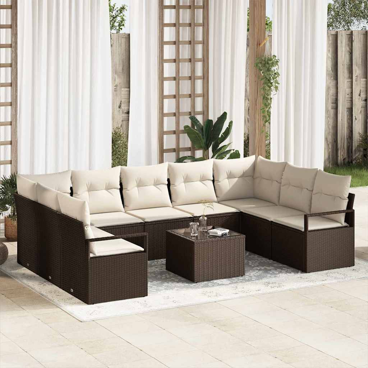 Sofá seccional para exteriores con cojines crema y una mesa de centro con tapa de vidrio, sobre una alfombra clara. Cortinas blancas al fondo.