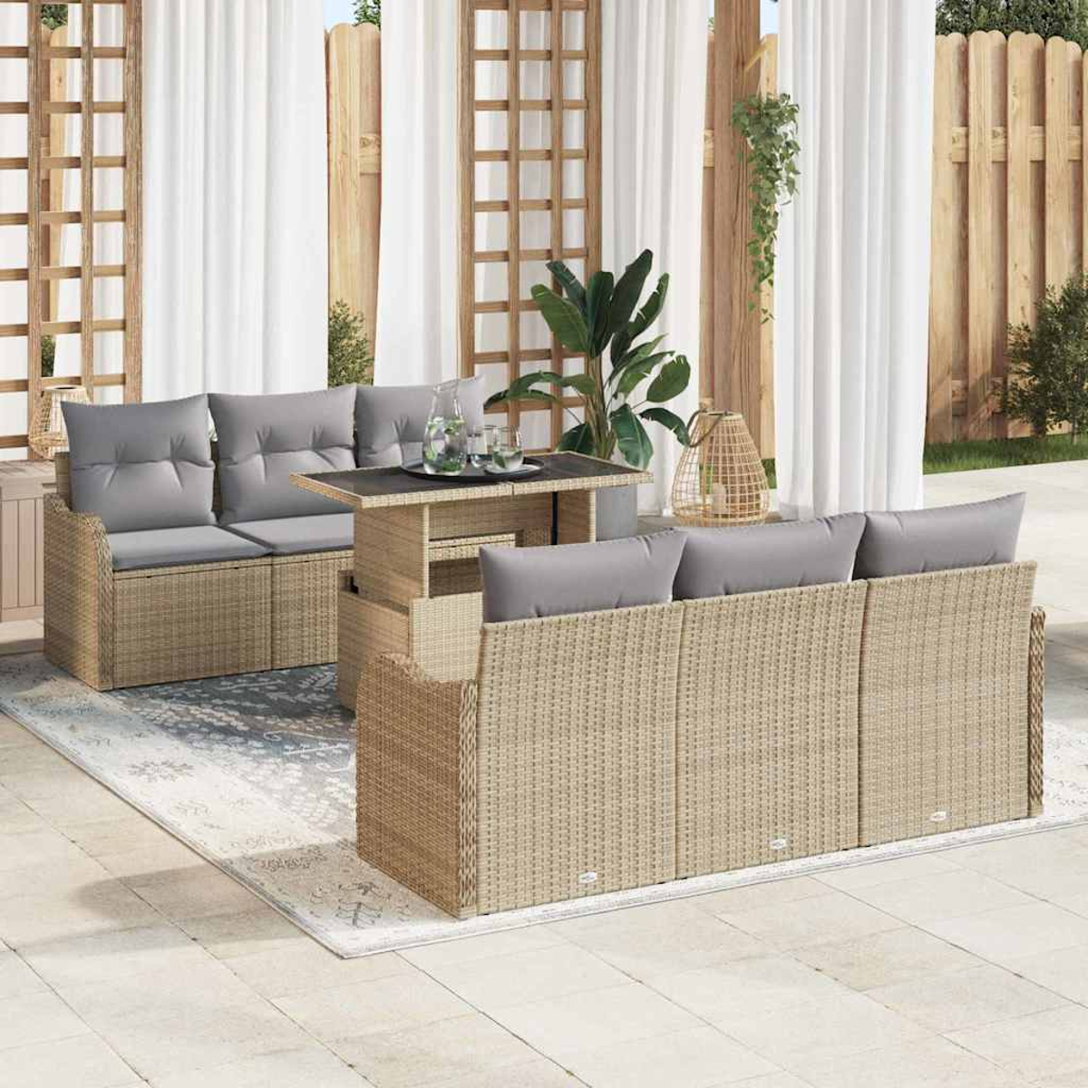 Garten-Wicker-Möbel-Set mit grauen Kissen. Enthält ein Sofa, einen Tisch und einen Teppich. Im Hintergrund weiße Vorhänge und Holzzaun.