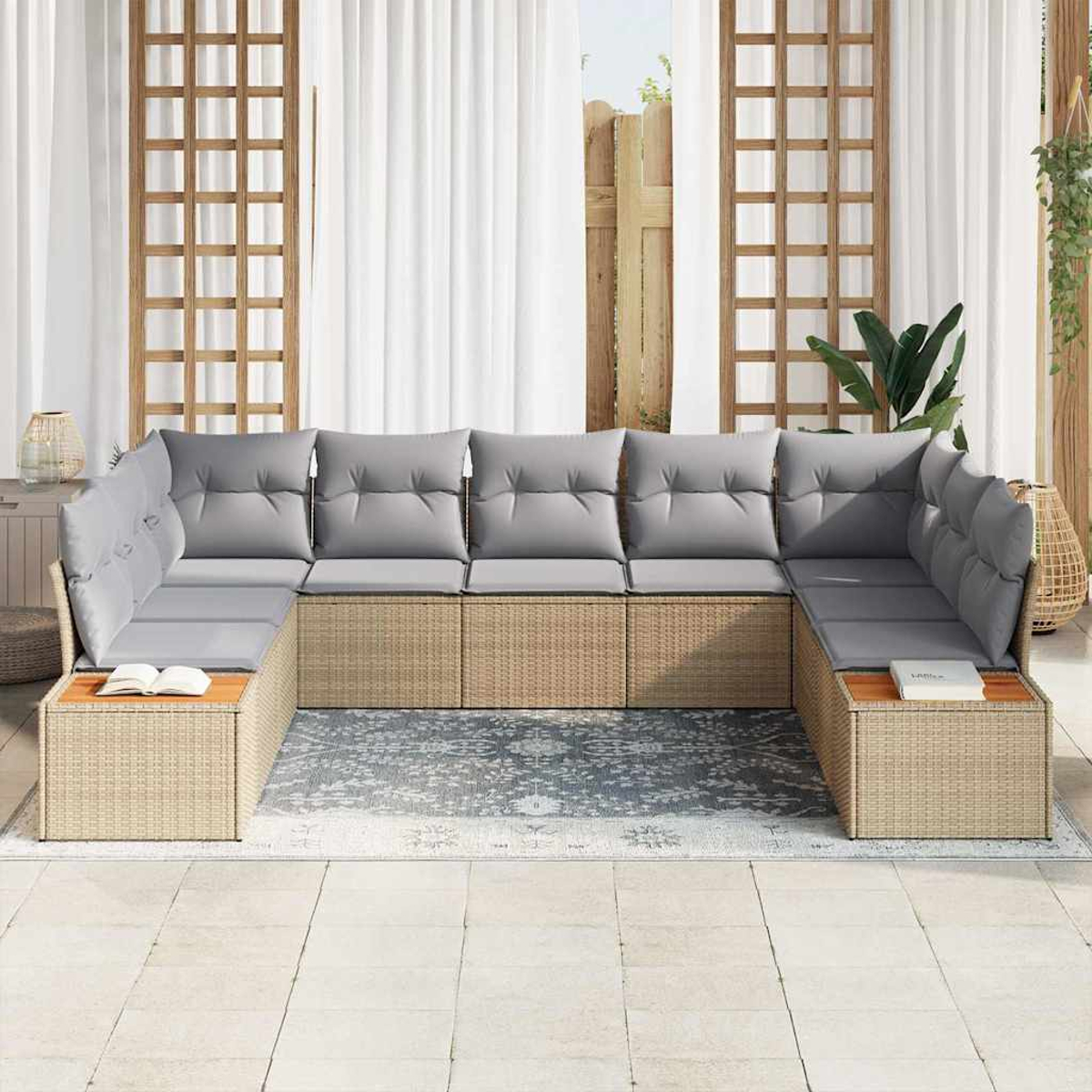 Ein U-förmiges Outdoor-Sofa mit grauen Kissen. Beiger Korbrahmen. Im Hintergrund ein Teppich und weiße Vorhänge. Zwei Bücher liegen auf den Tischen.