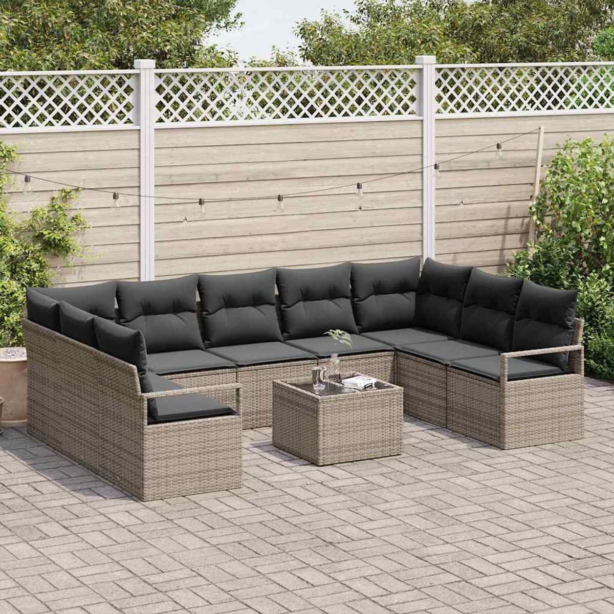 Geflochtenes Outdoor-Ecksofa mit dunkelgrauen Kissen und einem kleinen quadratischen Couchtisch. Es steht auf einer gepflasterten Terrasse mit Holzzaun dahinter.