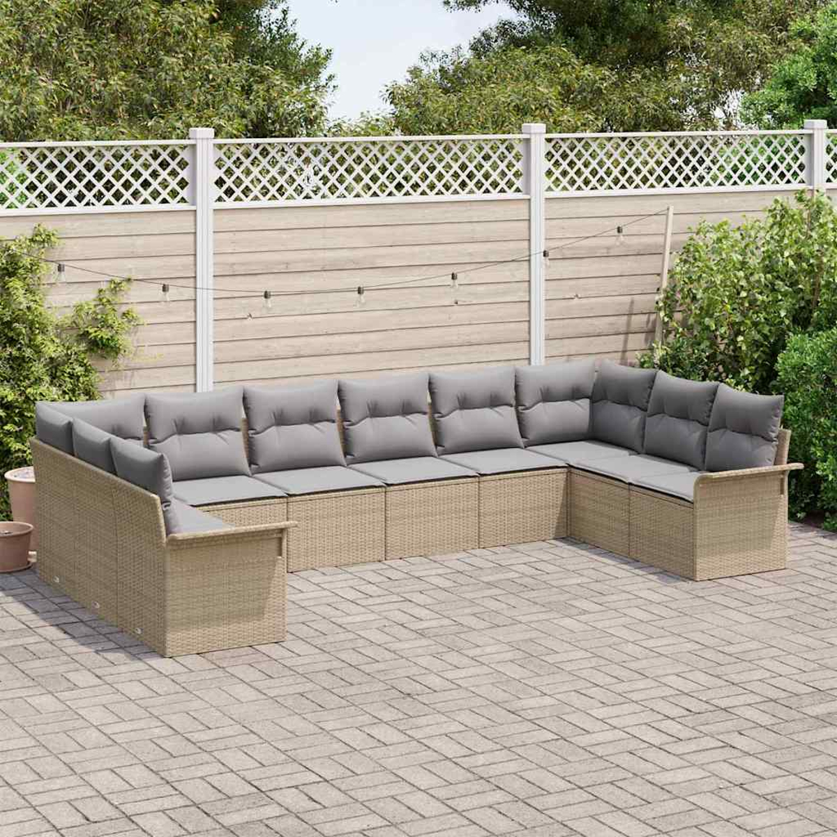 Ein beiges Rattan-Ecksofa mit grauen Kissen steht auf einer Ziegelterrasse. Ein Holzzaun und Grünzeug sind im Hintergrund.