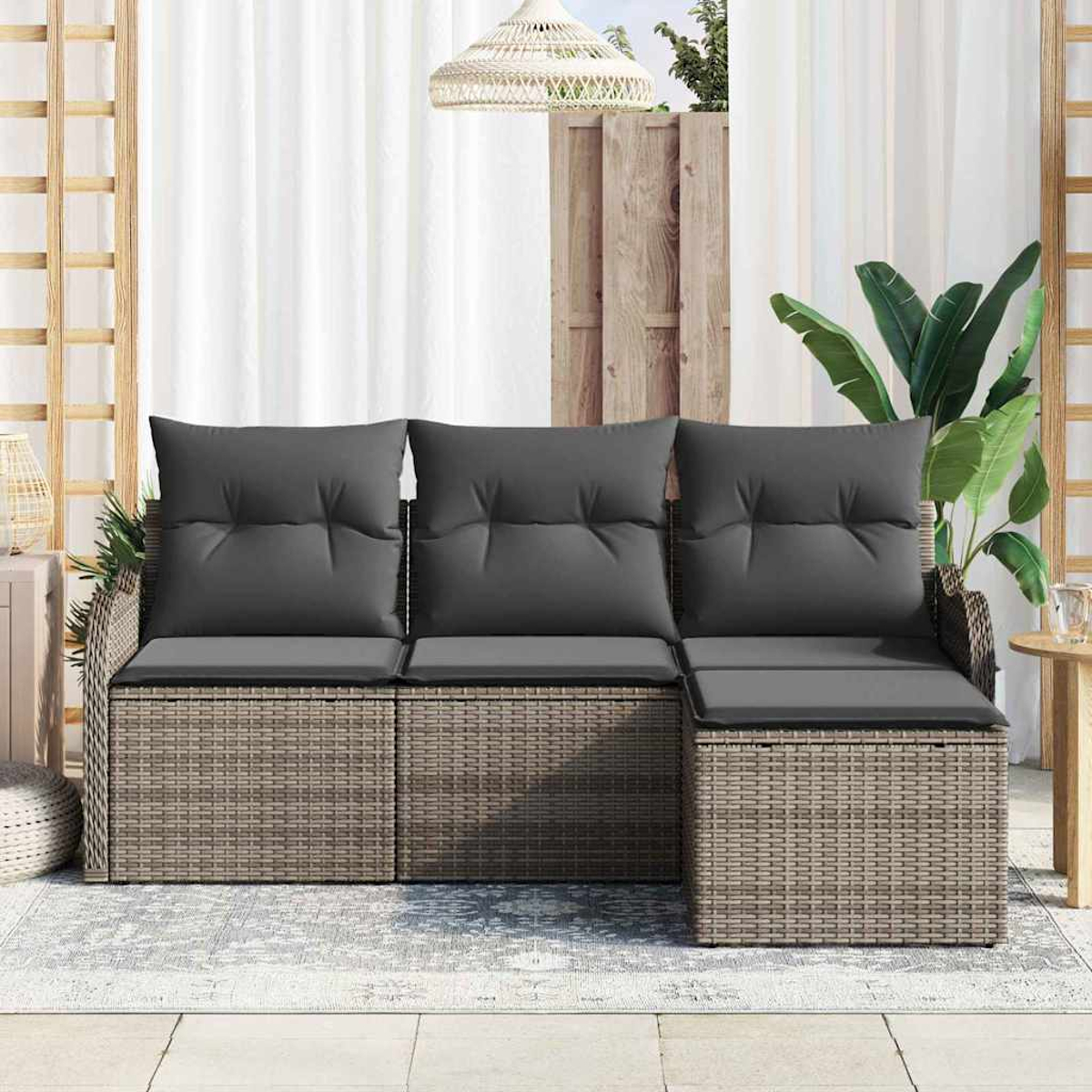 Outdoor-Korbsessel mit grauen Kissen. Weiße Vorhänge und ein Holzzaun sind im Hintergrund. Eine Pflanze und eine Lampe hängen darüber.