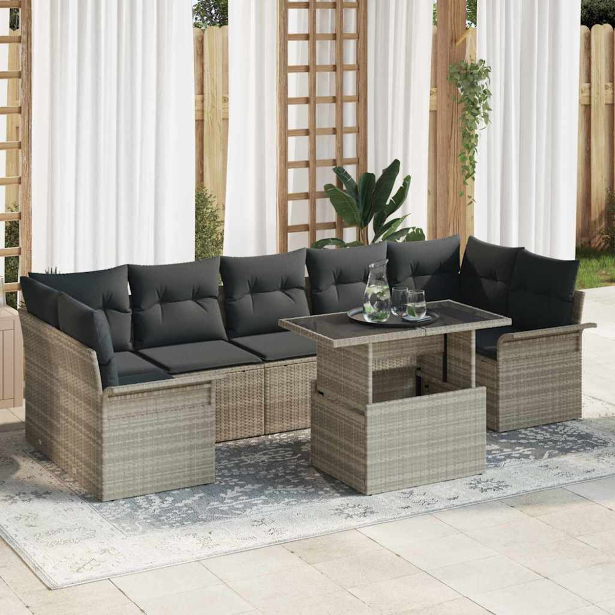 Garten-Terrassenset mit grauen Kissen, einem Hubtisch und einem Teppich. Weiße Vorhänge im Hintergrund. Pflanzen und Holzgitter sind sichtbar.