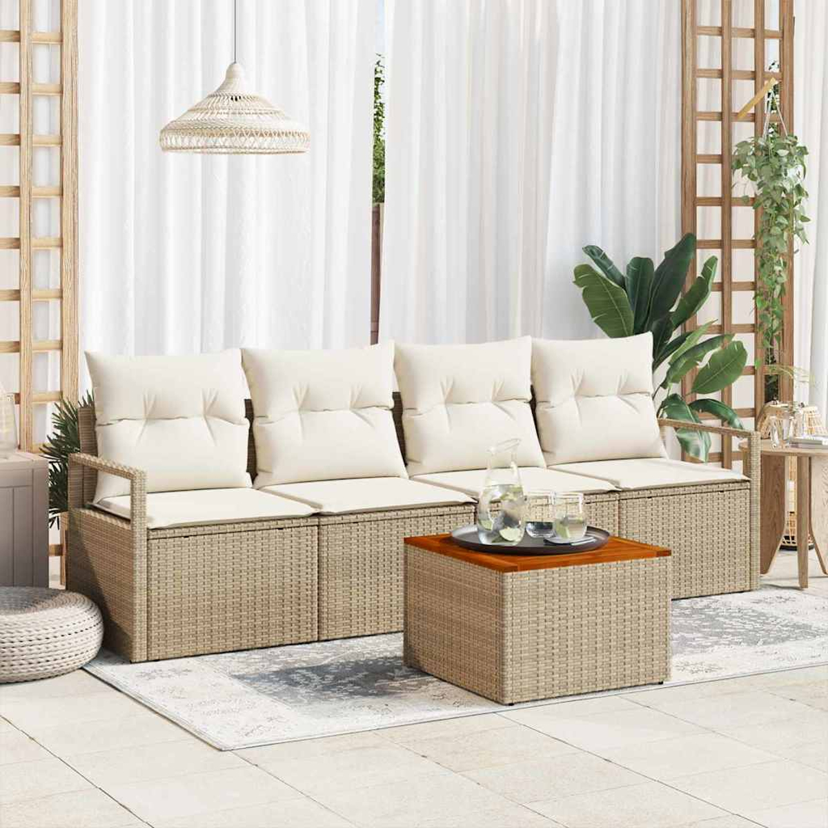 Gartenmöbel mit cremefarbenen Kissen, einem gewebten Couchtisch und einem weißen Vorhang im Hintergrund. Pflanzen und eine Hängeleuchte sind zu sehen.