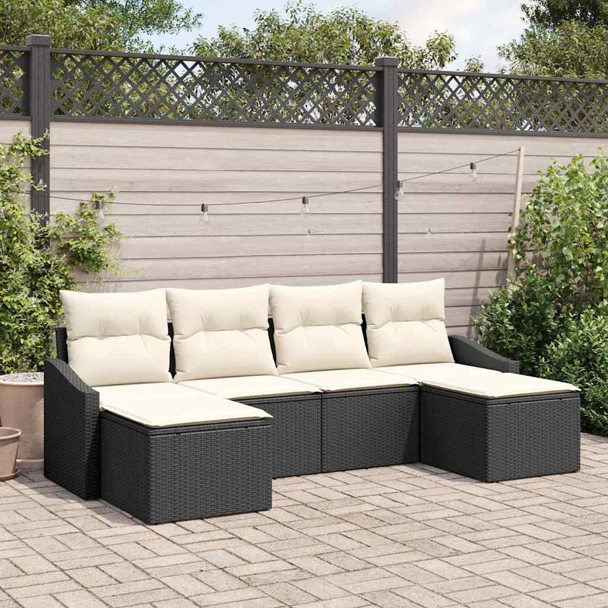 Ein schwarzes Outdoor-Ecksofa mit cremefarbenen Kissen steht auf einer Backstein-Terrasse. Ein Holzzaun und Grün bilden den Hintergrund.