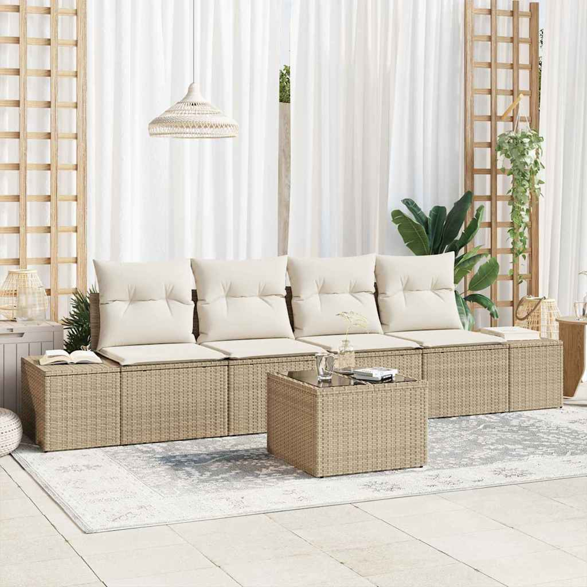 Beige Korbsessel mit weißen Kissen. Ein passender Couchtisch steht auf einem gemusterten Teppich. Weiße Vorhänge und Pflanzen im Hintergrund.