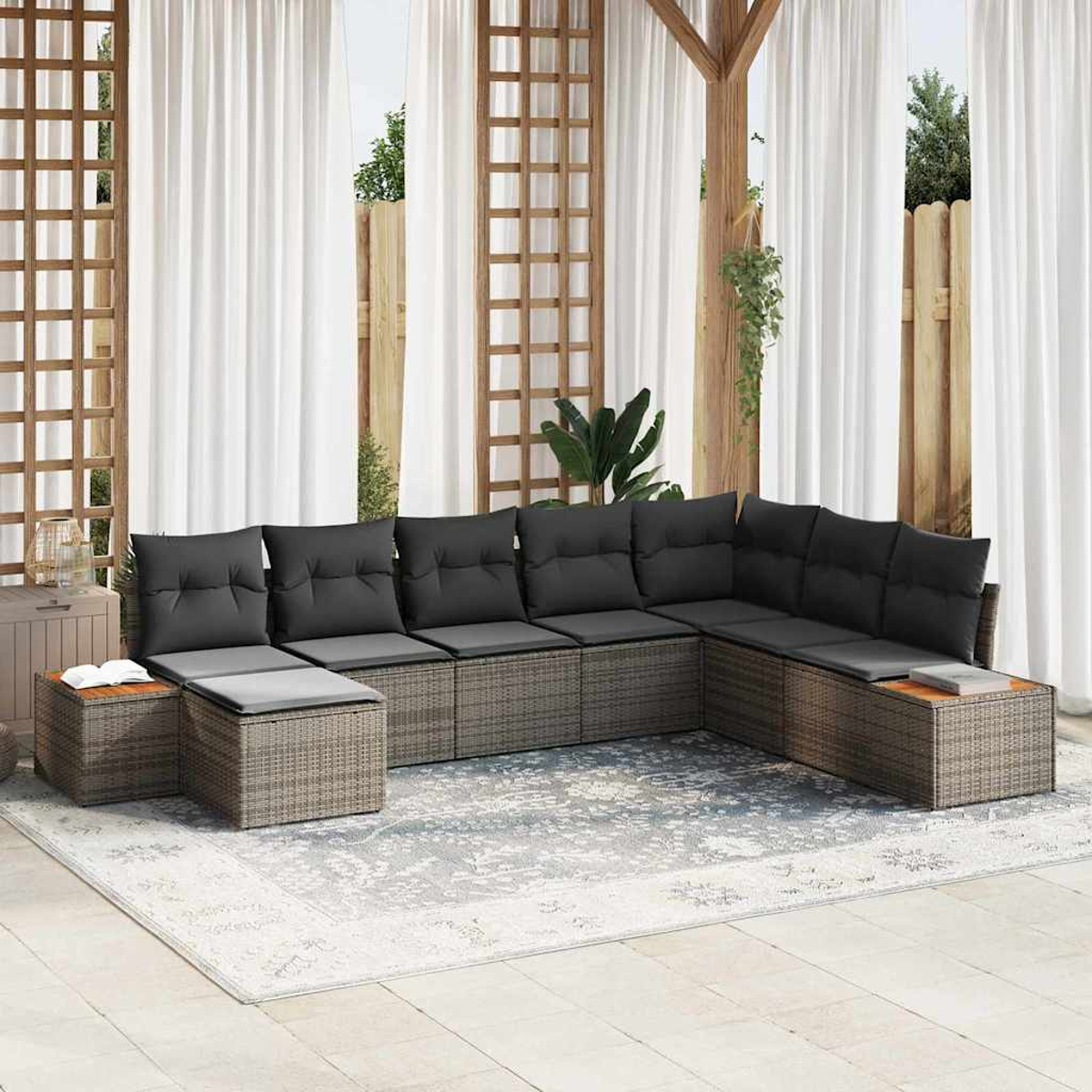 Ein Ecksofa im Freien mit grauen Kissen steht auf einem Teppich. Im Hintergrund befinden sich weiße Vorhänge, ein Holzgitter und ein Zaun.
