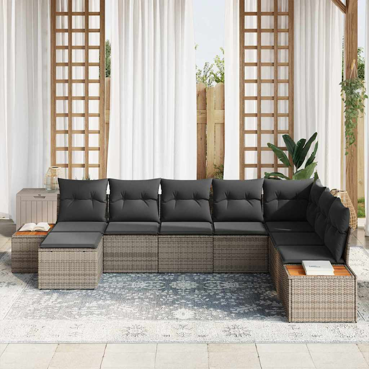 Outdoor-Ecksofa mit grauen Kissen auf einem gemusterten Teppich. Weiße Vorhänge und Holzgitter im Hintergrund. Beistelltische.
