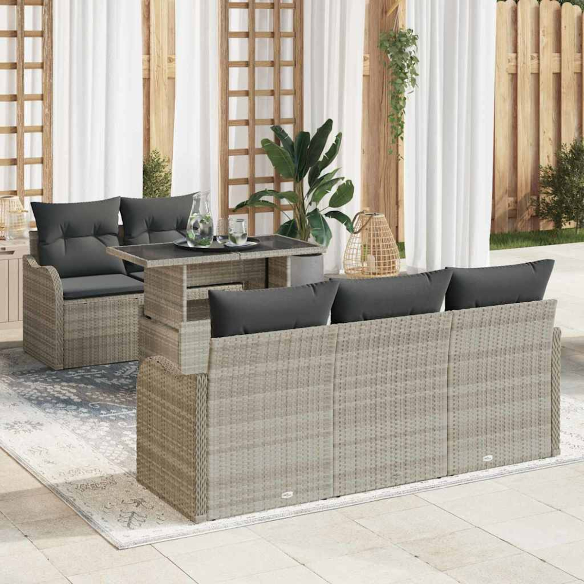 Garten-Sitzgruppe mit grauen Kissen auf einer Terrasse. Besteht aus Sofa, Stühlen und Tisch, umgeben von Pflanzen und Vorhängen.
