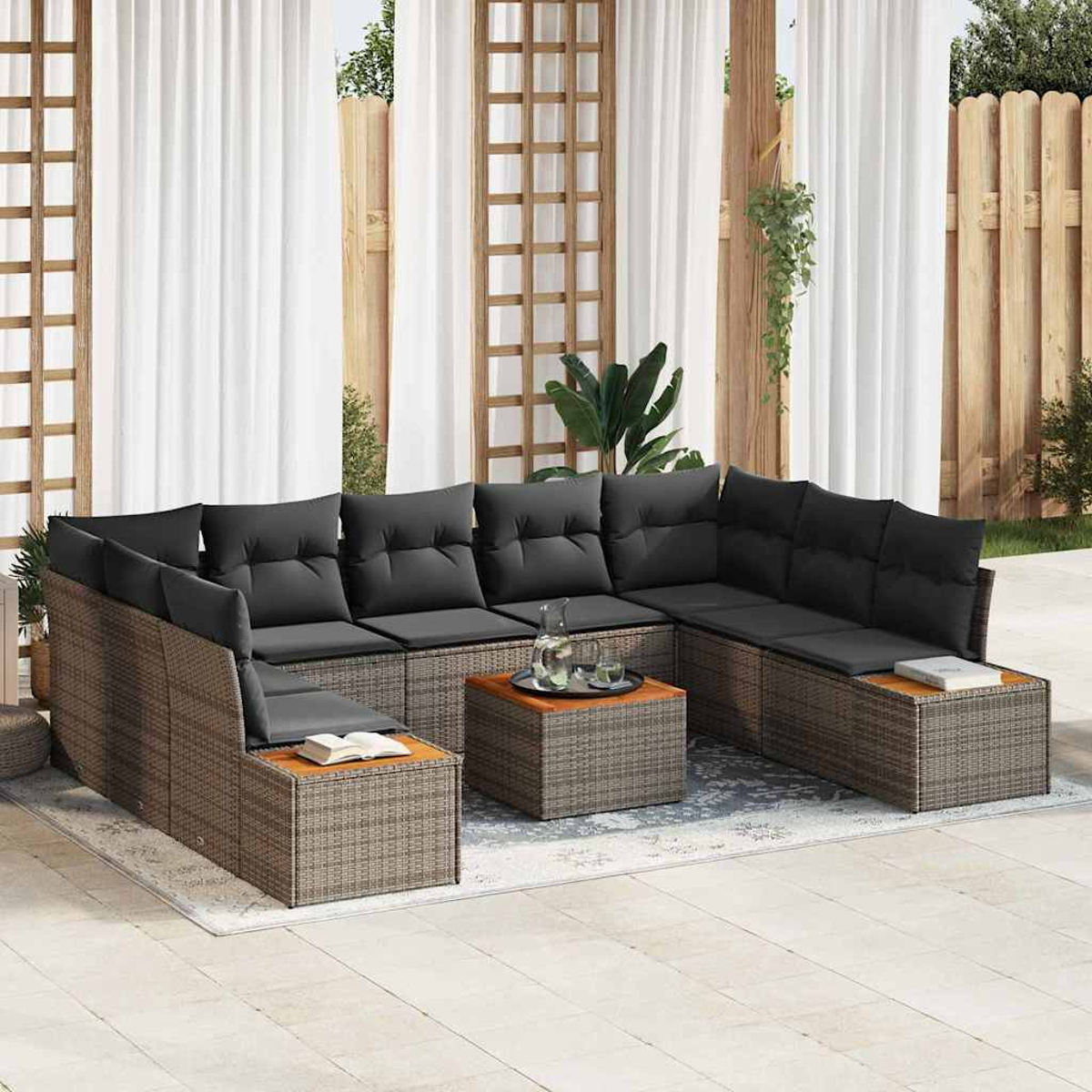 Outdoor-Ecksofa mit grauen Kissen und einem Holztisch, auf einer Terrasse mit weißen Vorhängen und Holzzaun im Hintergrund.