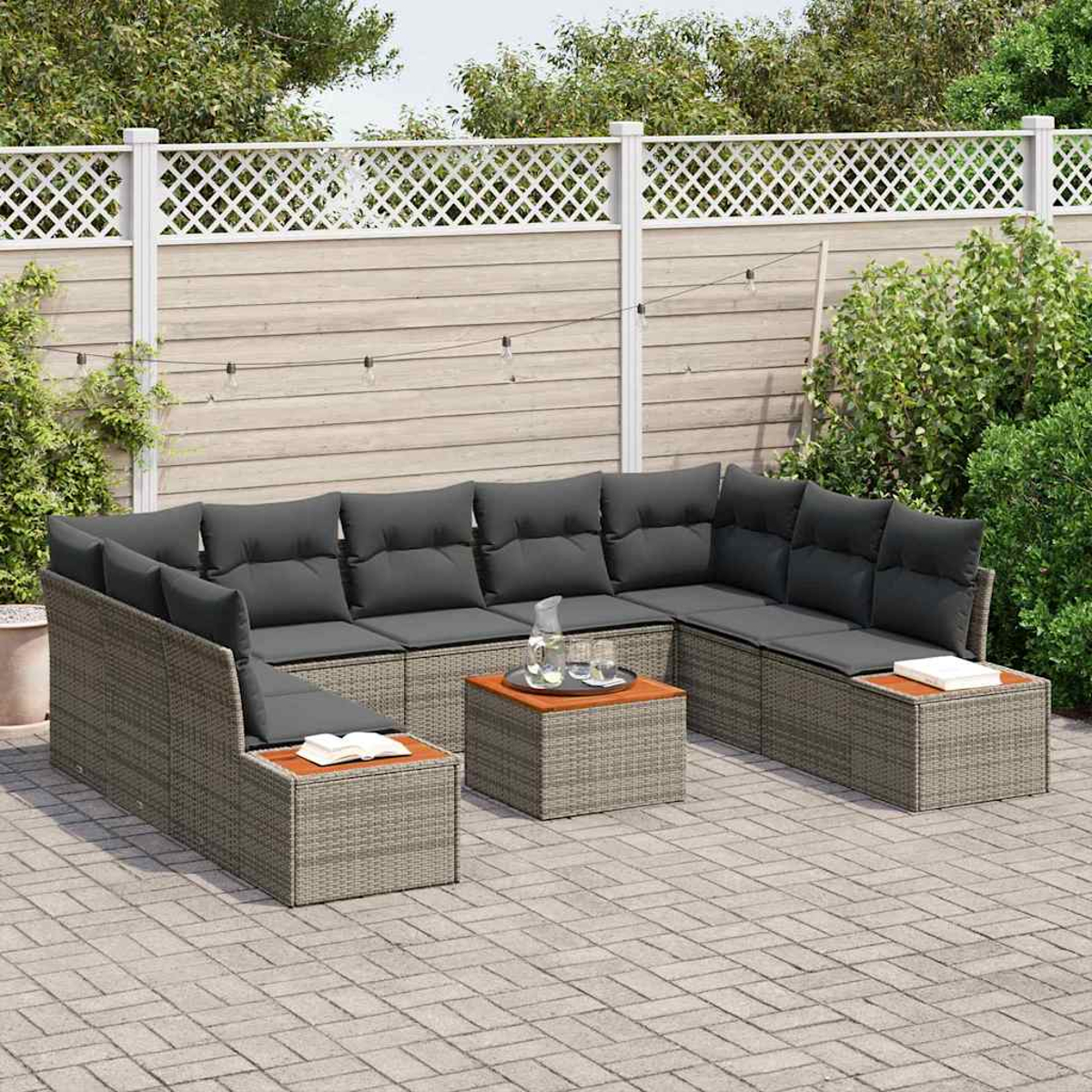 Outdoor-Ecksofa mit grauen Kissen und gewebtem Rahmen auf einer Terrasse. Ein Holztisch mit Glaskrug und Gläsern ist vorhanden.