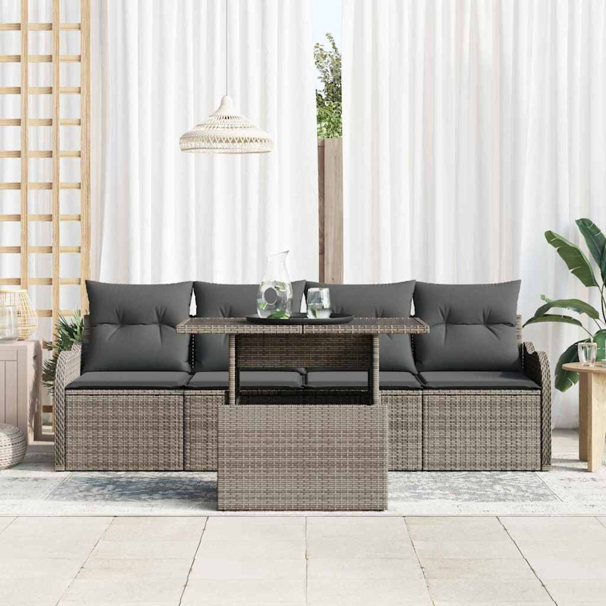 Gartenmöbel-Set mit grauen Kissen, einem Tisch mit Glaskrug und Gläsern sowie weißen Vorhängen im Hintergrund.