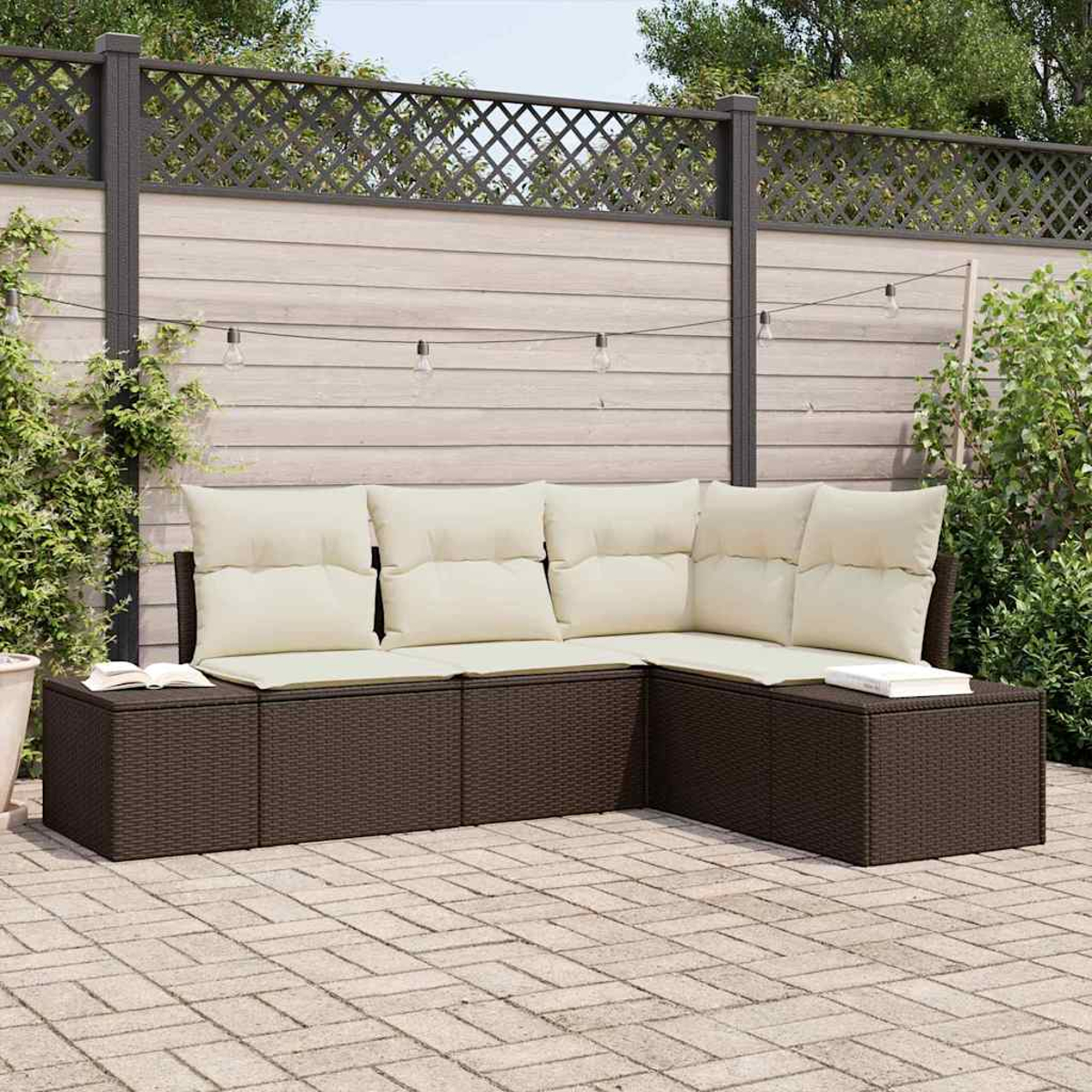 Outdoor-Ecksofa mit cremefarbenen Kissen auf einer Ziegelterrasse. Dunkelbraune Korbmöbel vor einem Holzzaun.