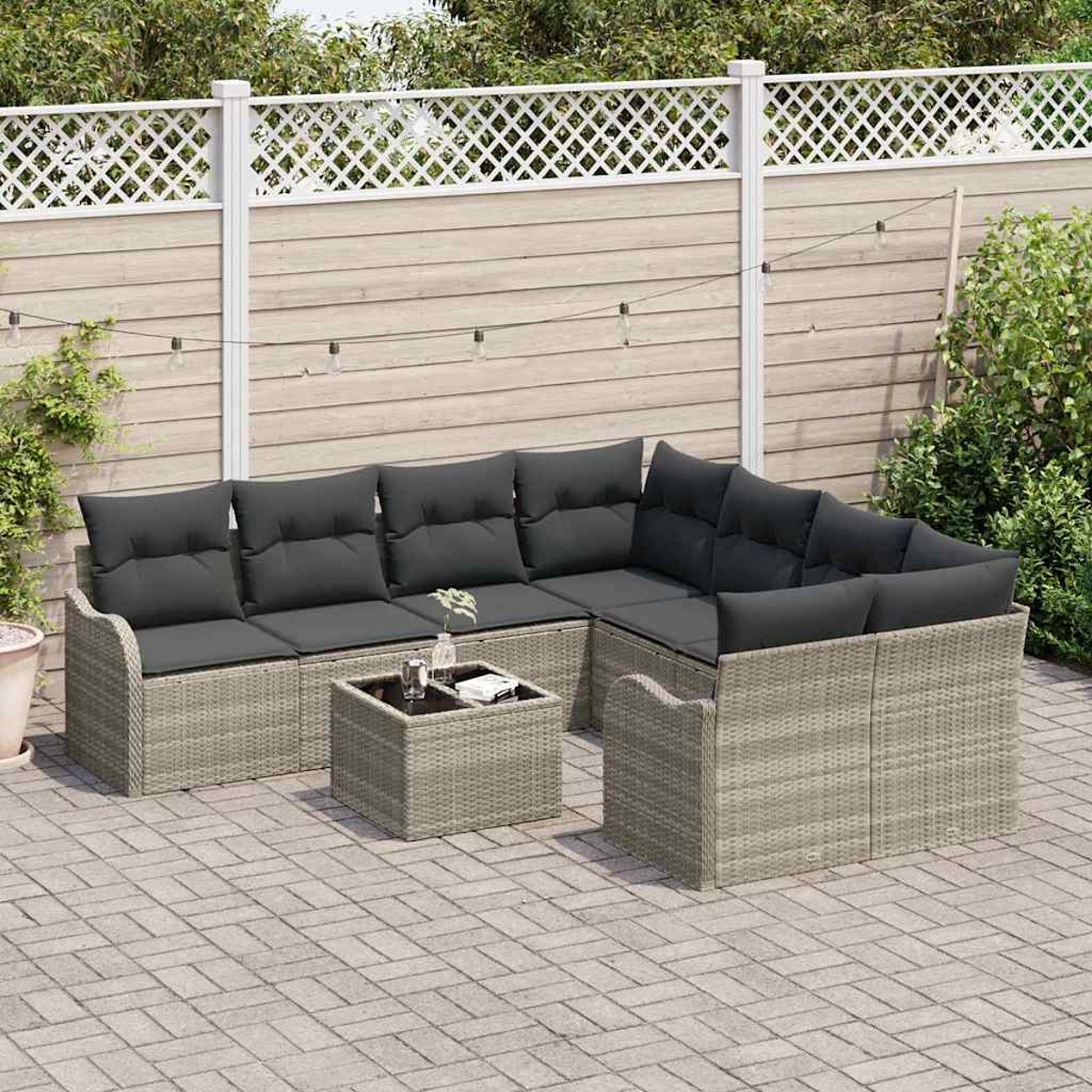 Outdoor-Rattansofa mit dunkelgrauen Kissen und einem kleinen Tisch. Holzzaun im Hintergrund, gepflasterte Terrasse.