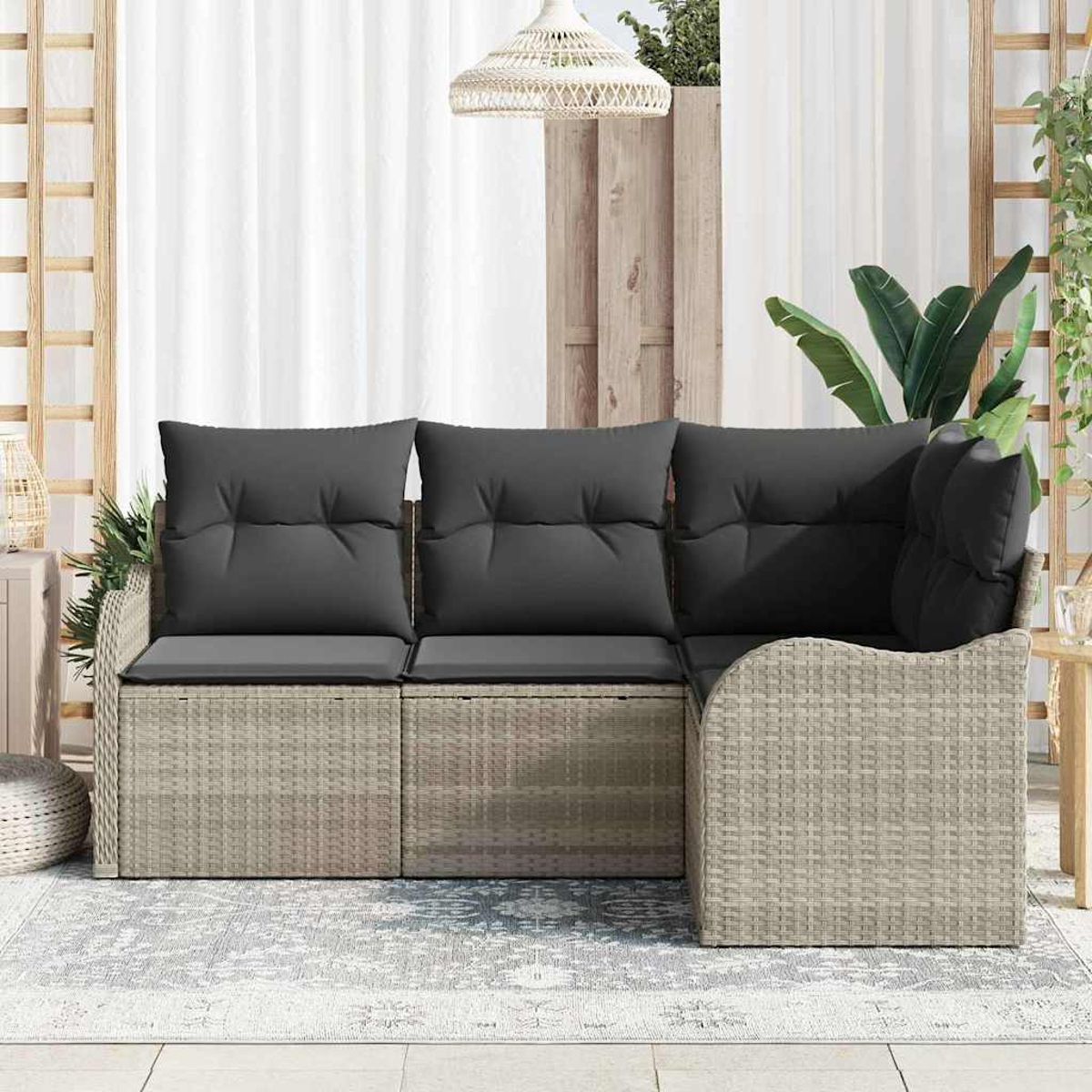 Ein Ecksofa mit grauen Kissen steht auf einem Teppich. Im Hintergrund befinden sich ein weißer Vorhang und eine Hängelampe.
