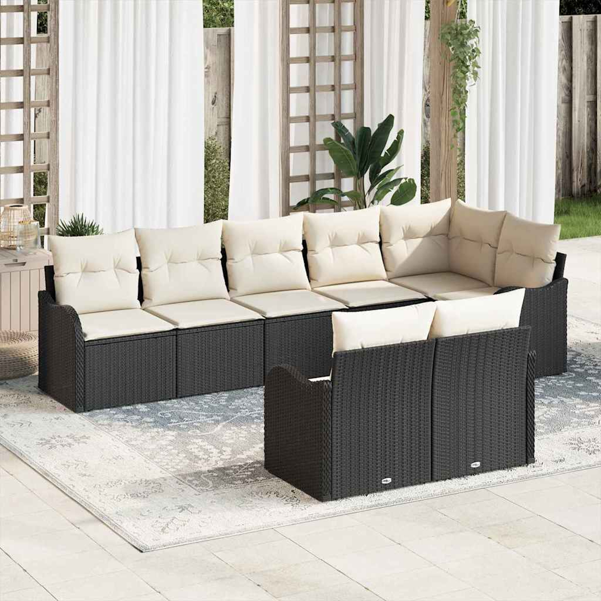Outdoor-Ecksofa mit cremefarbenen Kissen, dunklem Webrahmen, auf einem gemusterten Teppich. Weiße Vorhänge und Grün im Hintergrund.