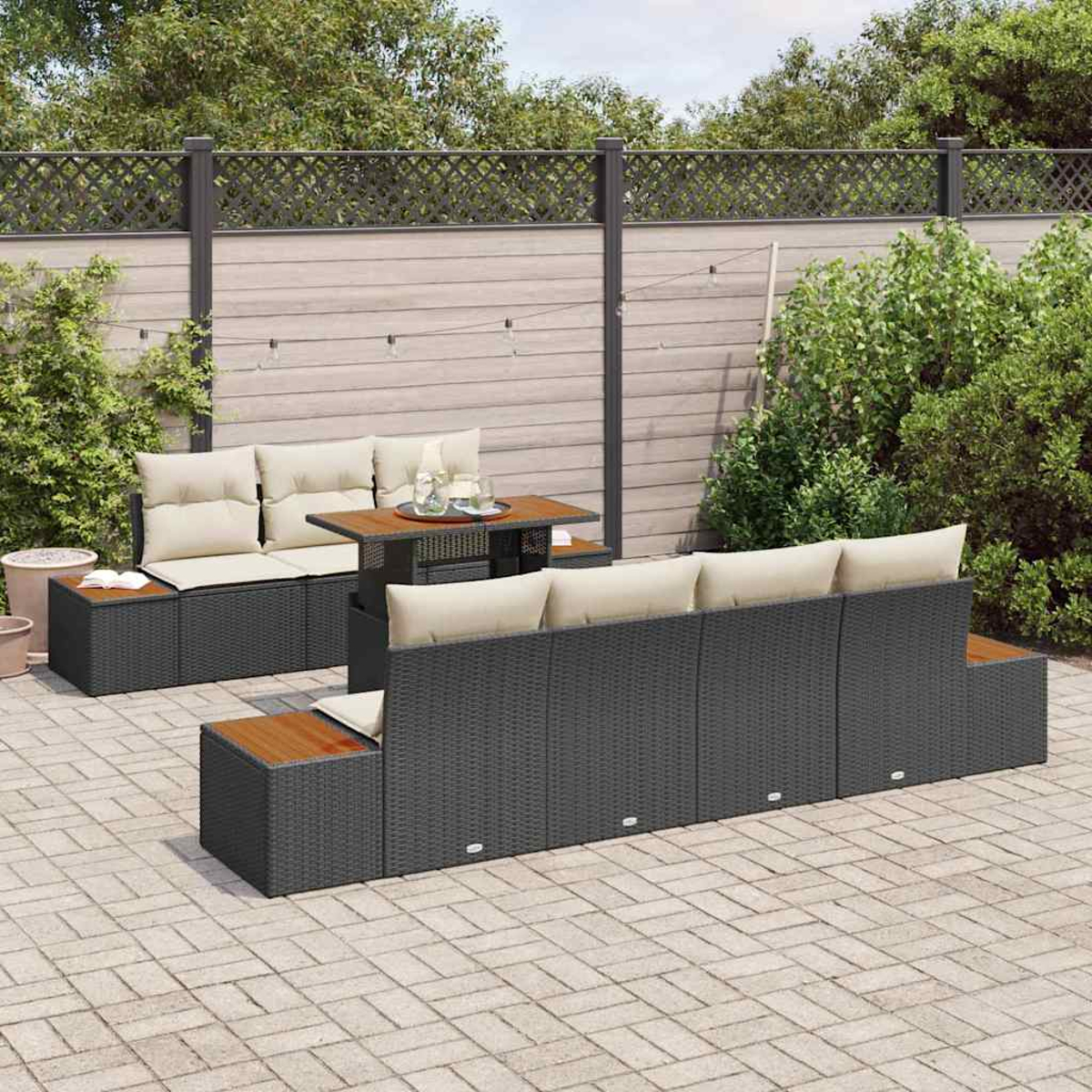 Garten-Sitzgruppe mit dunklem Korbgeflecht und beigefarbenen Kissen. Ein kleiner Tisch mit Glas und ein Zaun im Hintergrund.