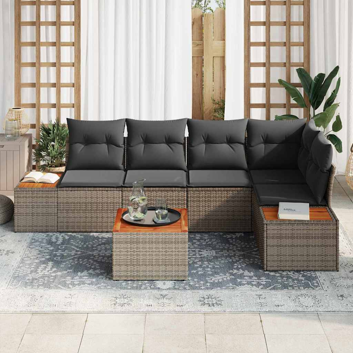 Outdoor-Ecksofa mit grauen Kissen, einem kleinen Tisch mit Getränken und einem gemusterten Teppich auf einer Terrasse.