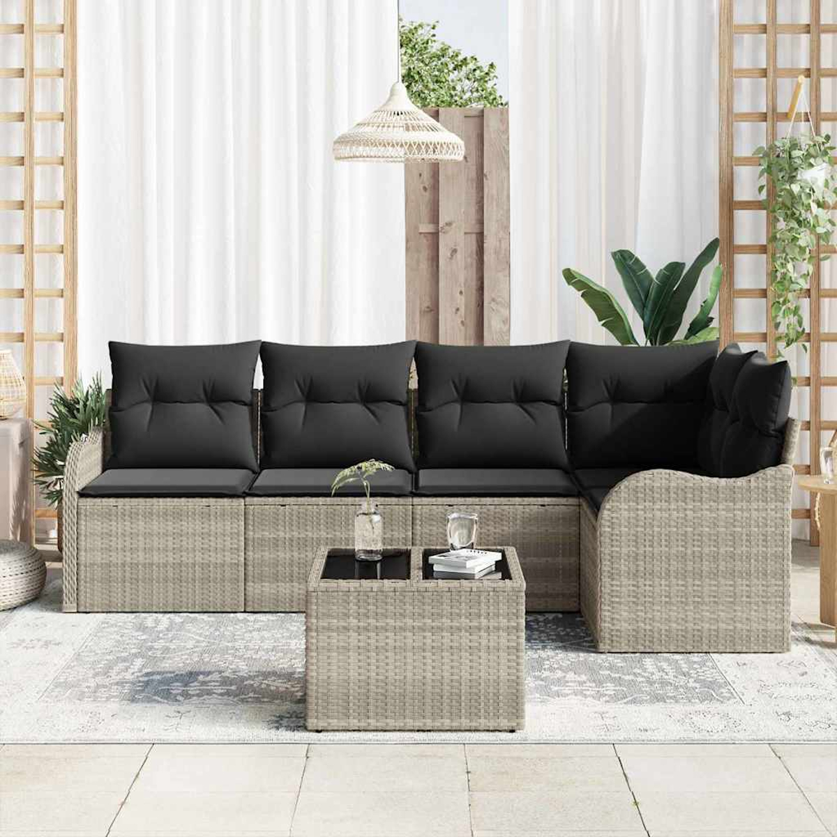 Outdoor-Ecksofa mit schwarzen Kissen und einem passenden Couchtisch. Die Szene umfasst Pflanzen und einen weißen Vorhang im Hintergrund.