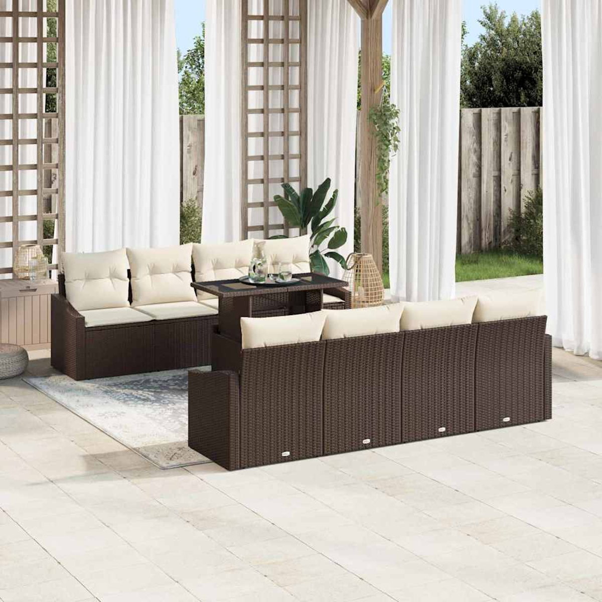 Garten-Sitzgruppe auf der Terrasse. Braune Korbsessel mit cremefarbenen Kissen, Tisch mit Getränken, weiße Vorhänge und Holzspalier.