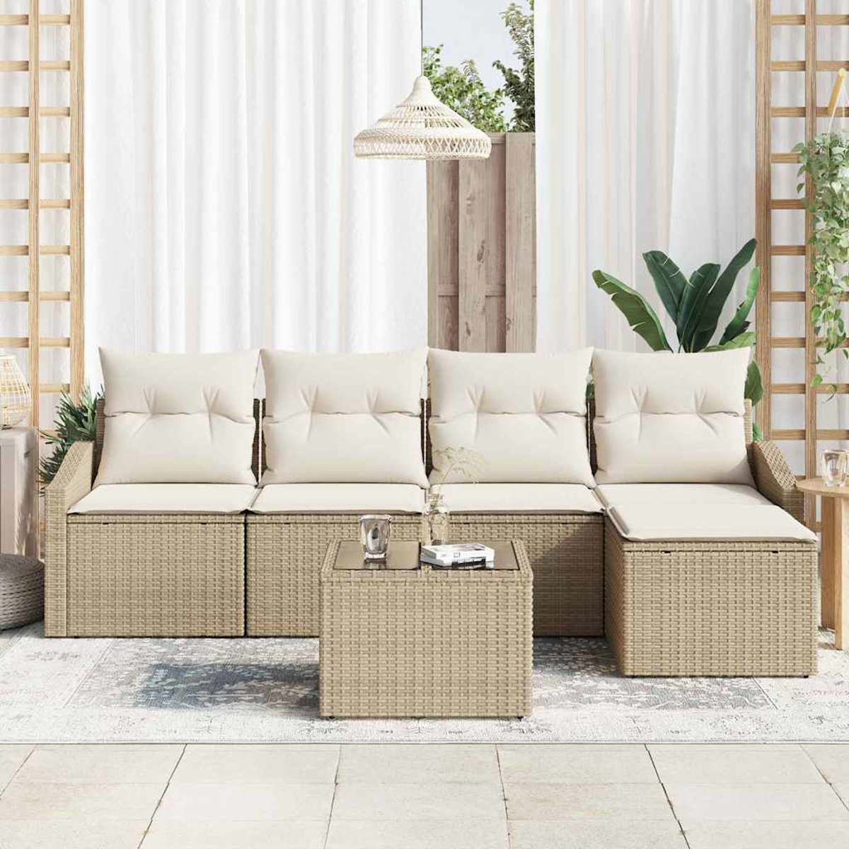 Outdoor-Korbsofa mit cremefarbenen Kissen und einem kleinen Tisch. Weiße Vorhänge und eine Hängelampe sind im Hintergrund.