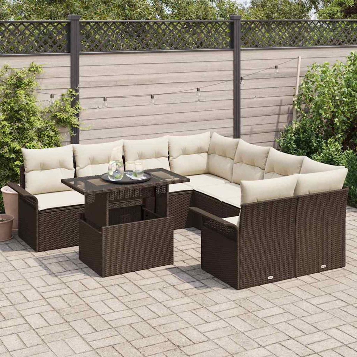 Gartenmöbel-Set mit braunem Korbgeflecht und beigen Kissen. Enthält einen Tisch mit Getränken und einen Zaun im Hintergrund.