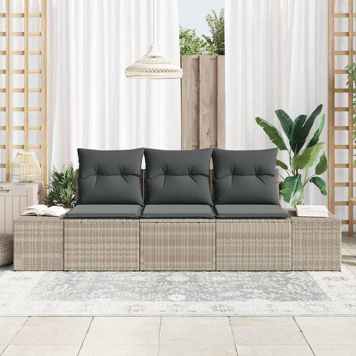 Rattansofa mit grauen Kissen vor Vorhängen. Eine Pflanze, Bücher und eine Lampe sind ebenfalls vorhanden. Der Boden ist gefliest.