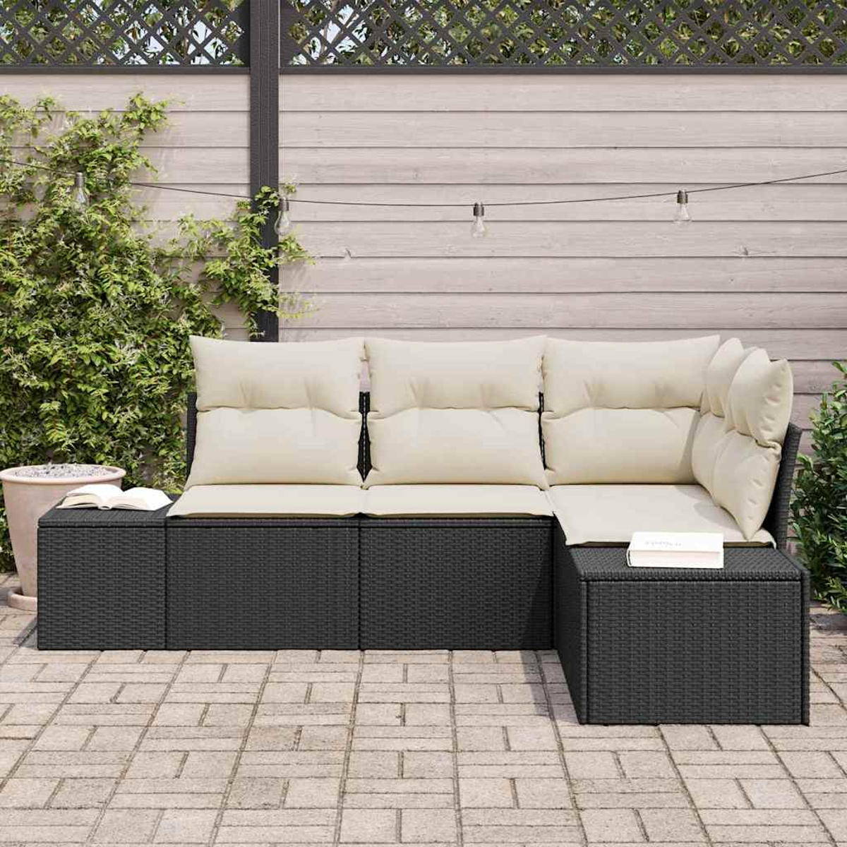 Ein Ecksofa im Freien mit cremefarbenen Kissen und einem dunklen Rahmen steht auf einer Ziegelterrasse. Ein Holzzaun und Pflanzen sind im Hintergrund.