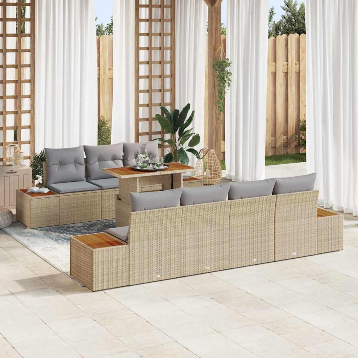Gartenmöbel-Set aus Weide mit grauen Kissen, einem Holztisch und weißen Vorhängen im Hintergrund. Holzzaun sichtbar.
