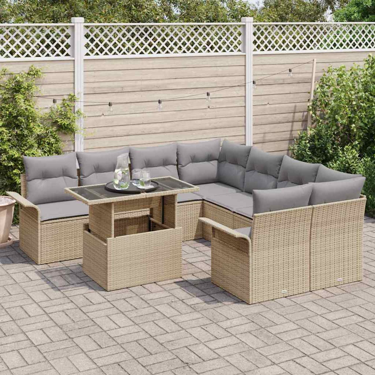 Gartenmöbel-Set aus Korbgeflecht. Graue Kissen auf beigen Sitzgelegenheiten. Glastisch mit Getränken. Holzzaun im Hintergrund.
