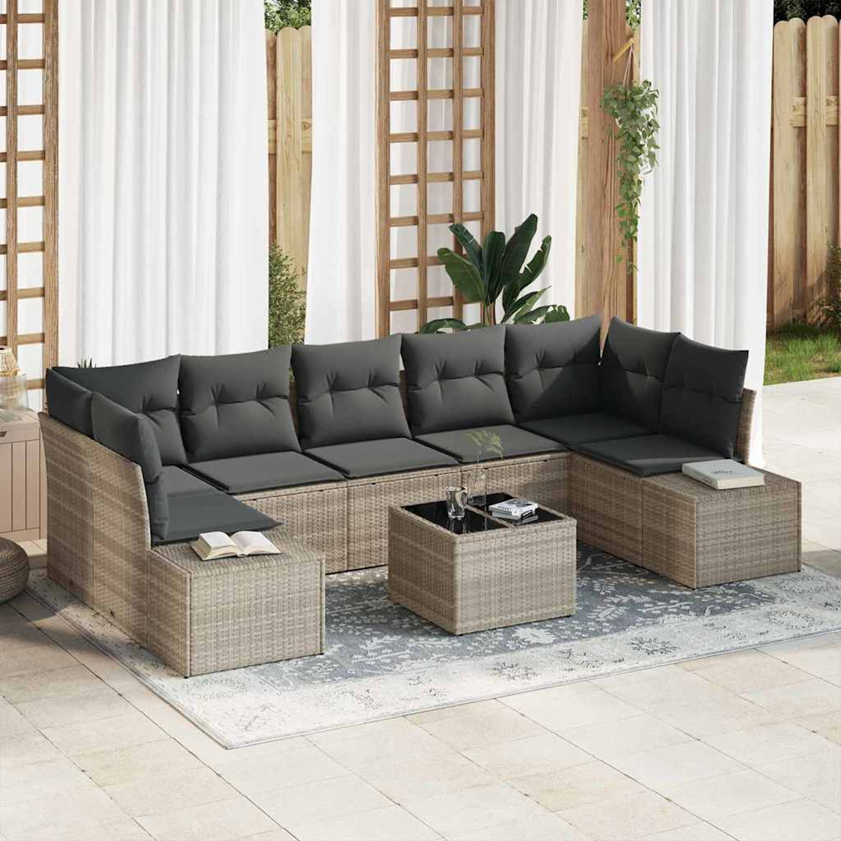 Ein Ecksofa mit grauen Kissen und ein kleiner Tisch stehen auf einem Teppich. Im Hintergrund befinden sich Vorhänge und Holzstrukturen.