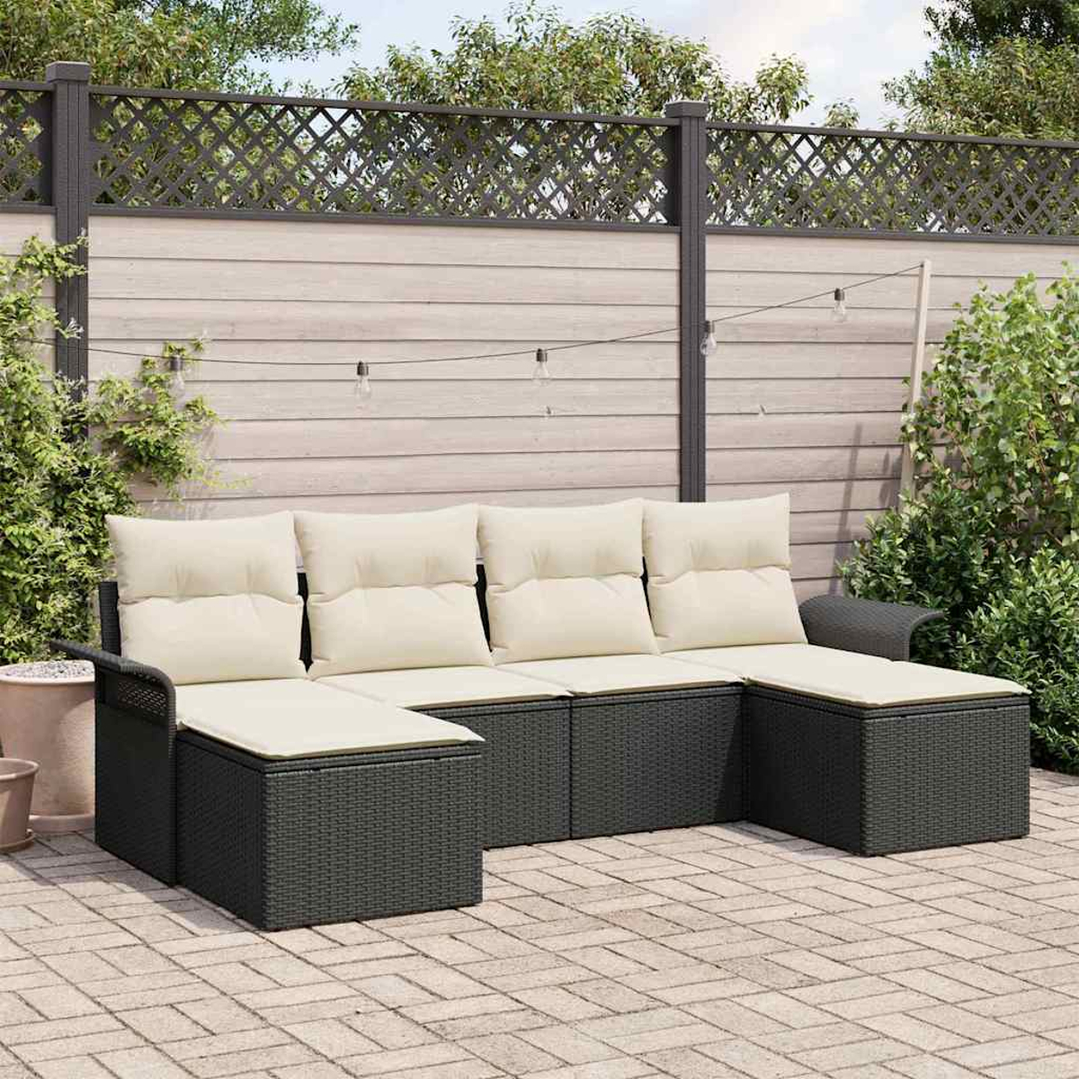 Outdoor-Ecksofa mit cremefarbenen Kissen auf einer Backstein-Terrasse. Holzzaun und Grün im Hintergrund.