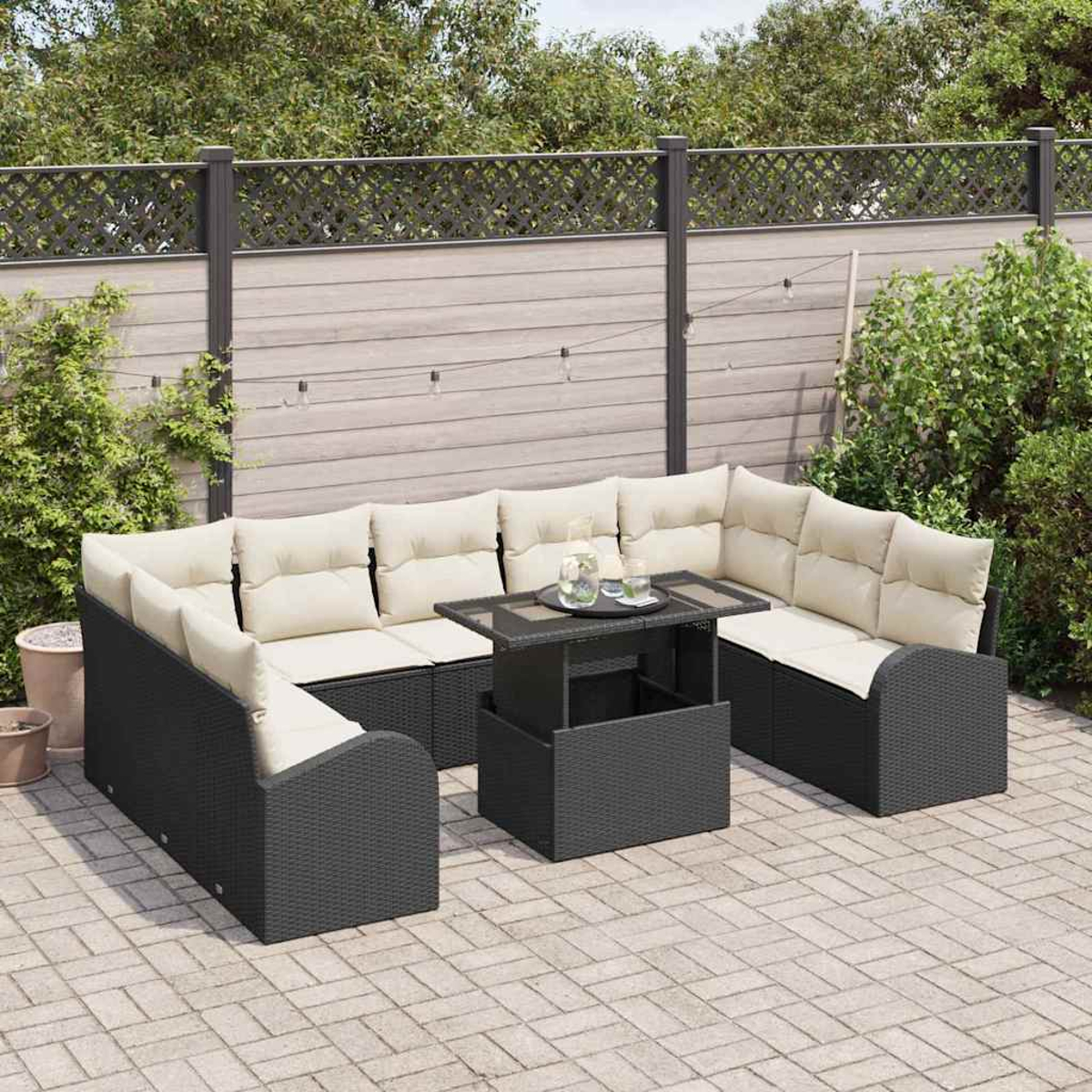 Outdoor-Ecksofa mit cremefarbenen Kissen und einem schwarzen Tisch auf einer Terrasse. Im Hintergrund ein Zaun und Grün.