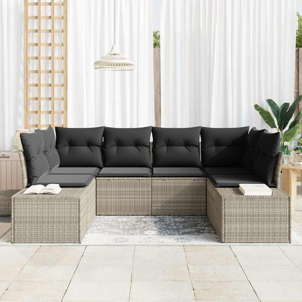Outdoor-Ecksofa mit schwarzen Kissen. Weiße Vorhänge im Hintergrund. Ein Buch liegt auf der Seite. Eine Hängelampe ist sichtbar.