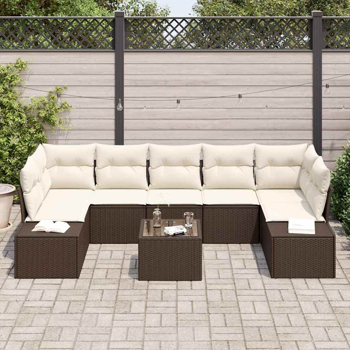 Ein Ecksofa im Freien mit cremefarbenen Kissen und einem braunen Korbbas. Ein kleiner Tisch mit Getränken und Büchern steht vor dem Sofa.