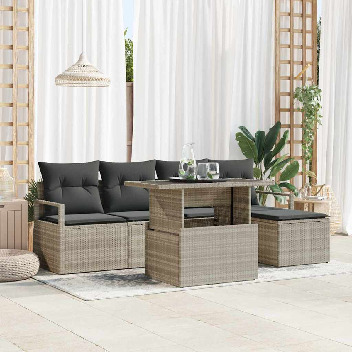 Gartenmöbel-Set mit grauen Kissen und einem Tisch. Weiße Vorhänge im Hintergrund. Eine gewebte Lampe hängt oben.