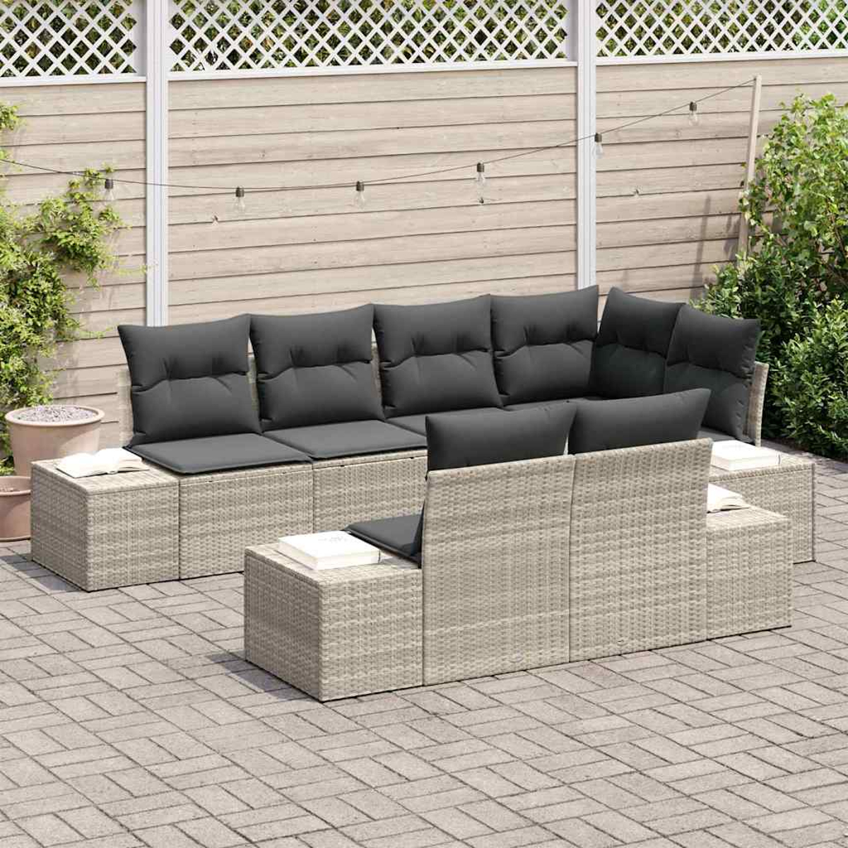 Outdoor-Wicker-Möbel-Set mit grauen Kissen. Enthält Sofa, Ottomanen und einen Stuhl mit niedrigem Rücken. Auf einer Ziegelsteinterrasse mit Holzzaun.